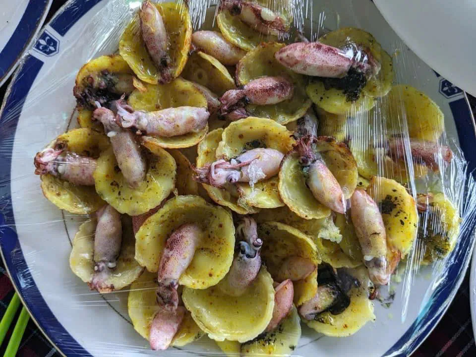 Đĩa bánh căn mực chín vàng, mỗi cái bánh có một con mực tươi nằm trên