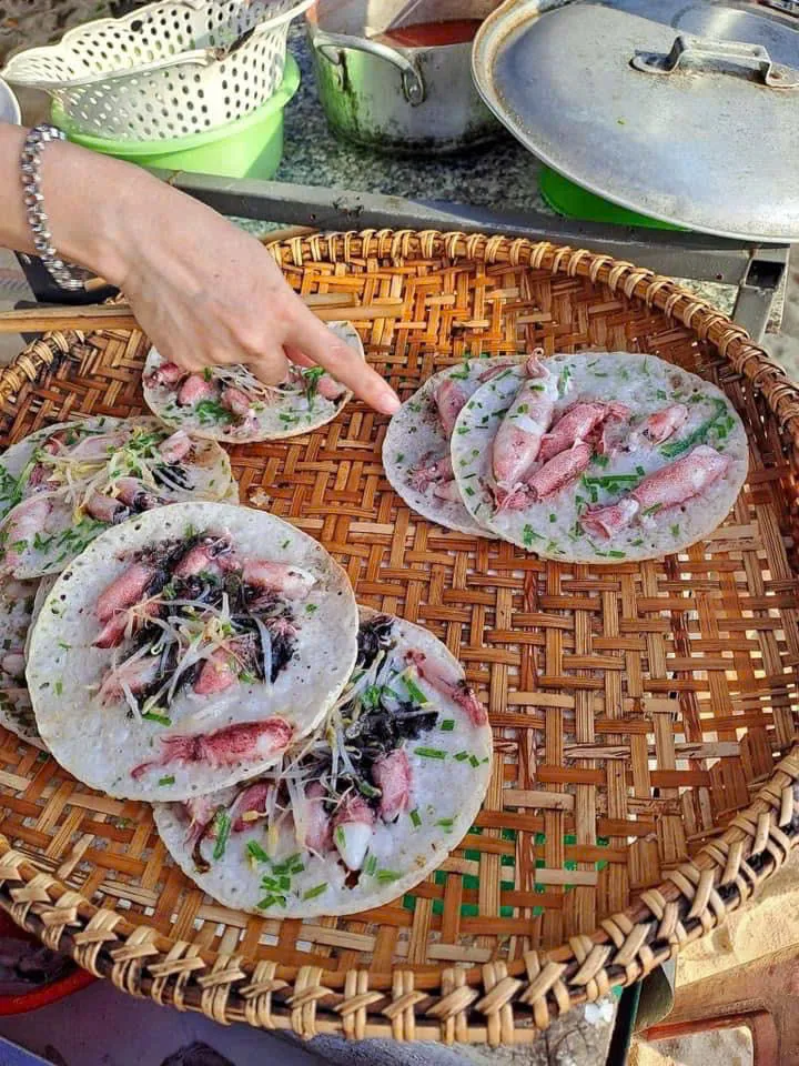 Bánh xèo mực nhảy đang chuẩn bị trên nia tre: mực và tôm tươi xếp lên từng cái bánh cùng hẹ và giá