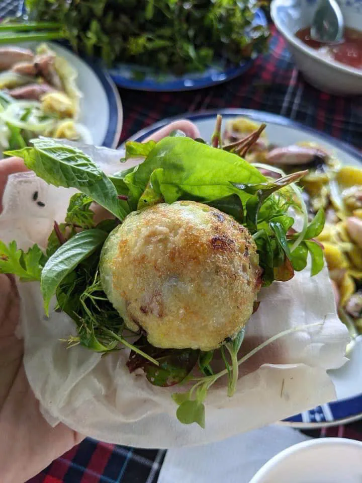 Bánh xèo mực nhảy cuốn bánh tráng kèm rau sống, cầm trên tay